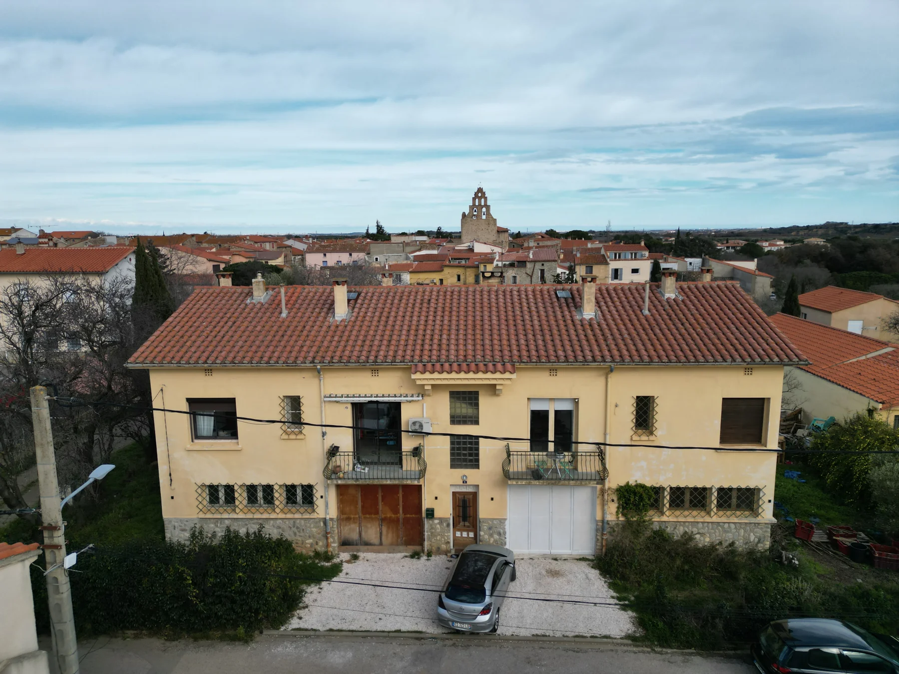 Maison avant rénovation avec façade jaune vieillie, deux balcons et ancien accès de garage