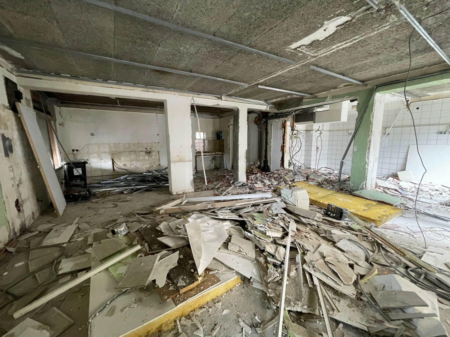 Bureau en travaux avec cloisons déposées, plafond brut et gravats au sol