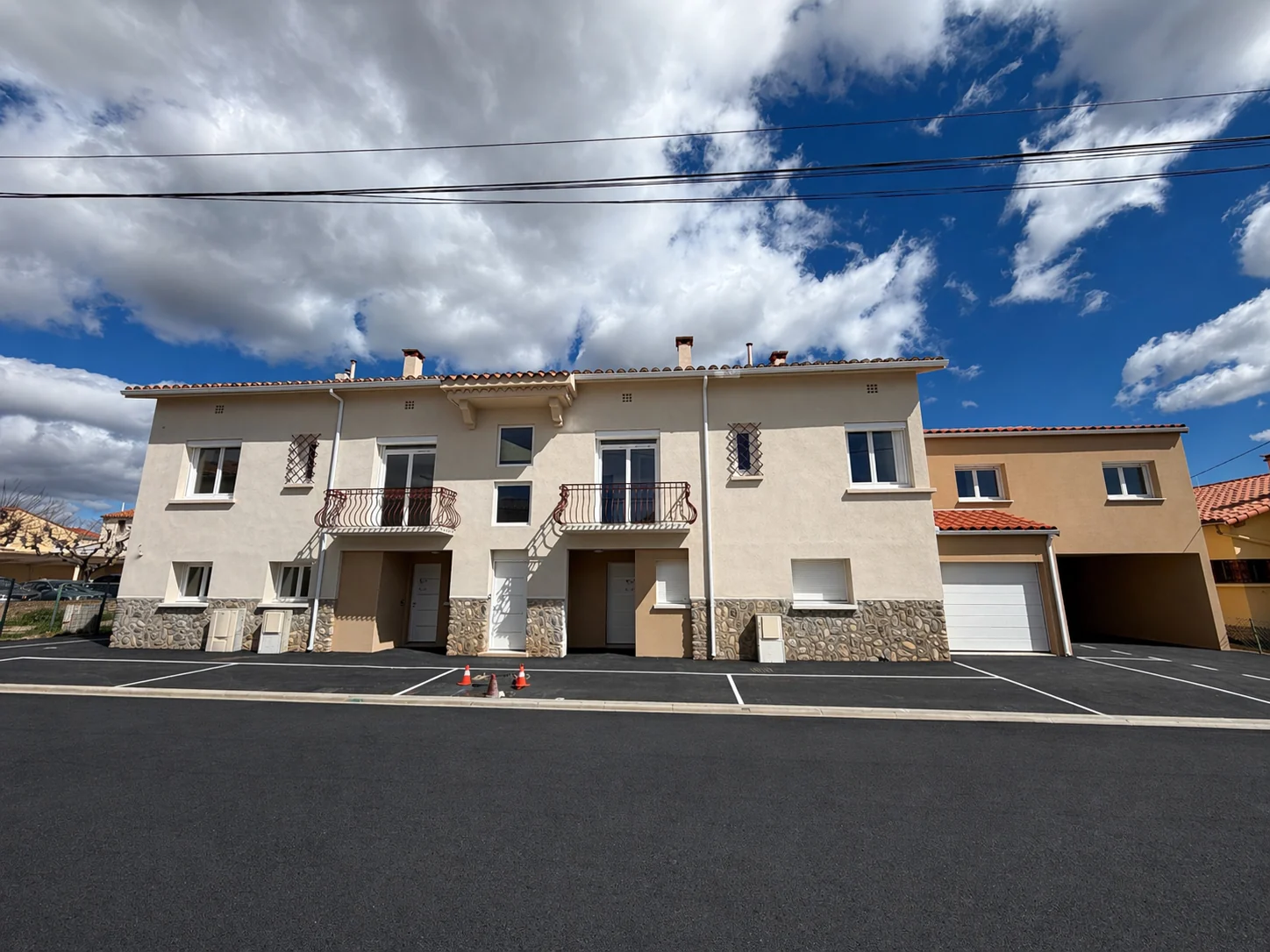Maison après rénovation avec enduit clair, balcons conservés, nouvelles ouvertures et abords aménagés